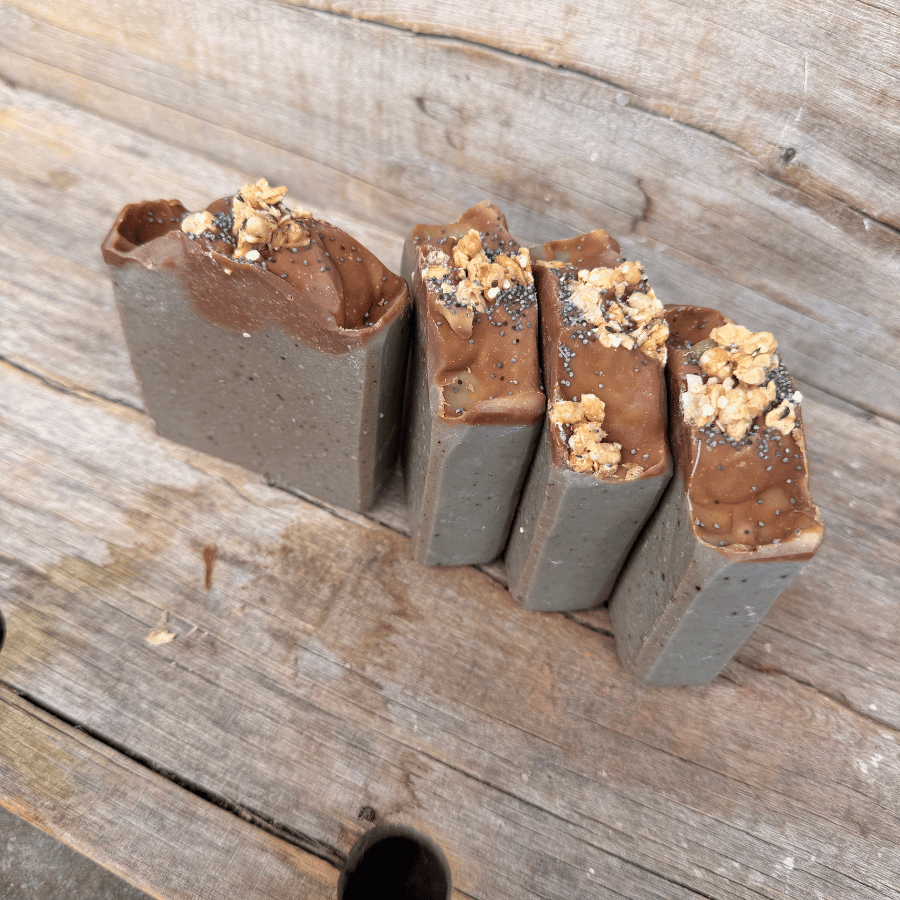 Small-batch Blueberry Muffin tallow soap bars topped with blueberry oat granola and poppy seeds on rustic wood.