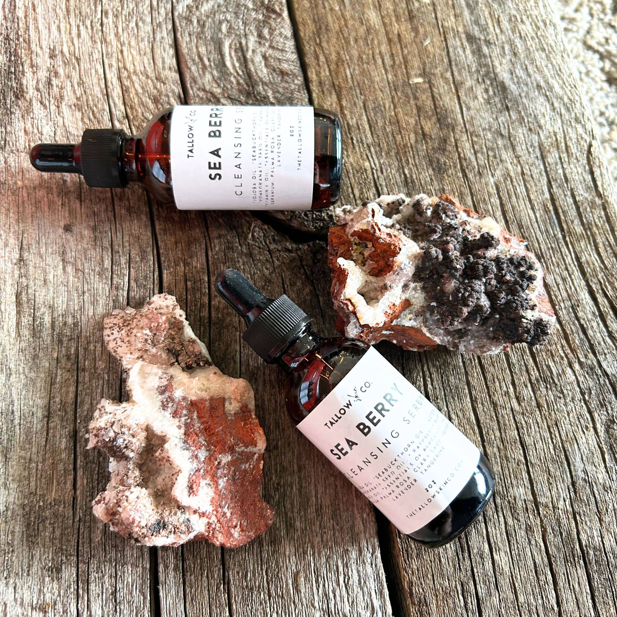 Sea buckthorn oil cleanser laying on barn wood between crystals.