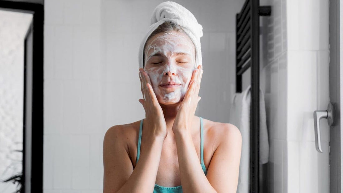 women washing her face in the bathroom wearing her hair up in a towel wrap