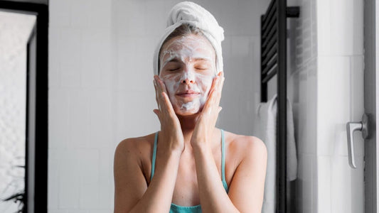 women washing her face in the bathroom wearing her hair up in a towel wrap