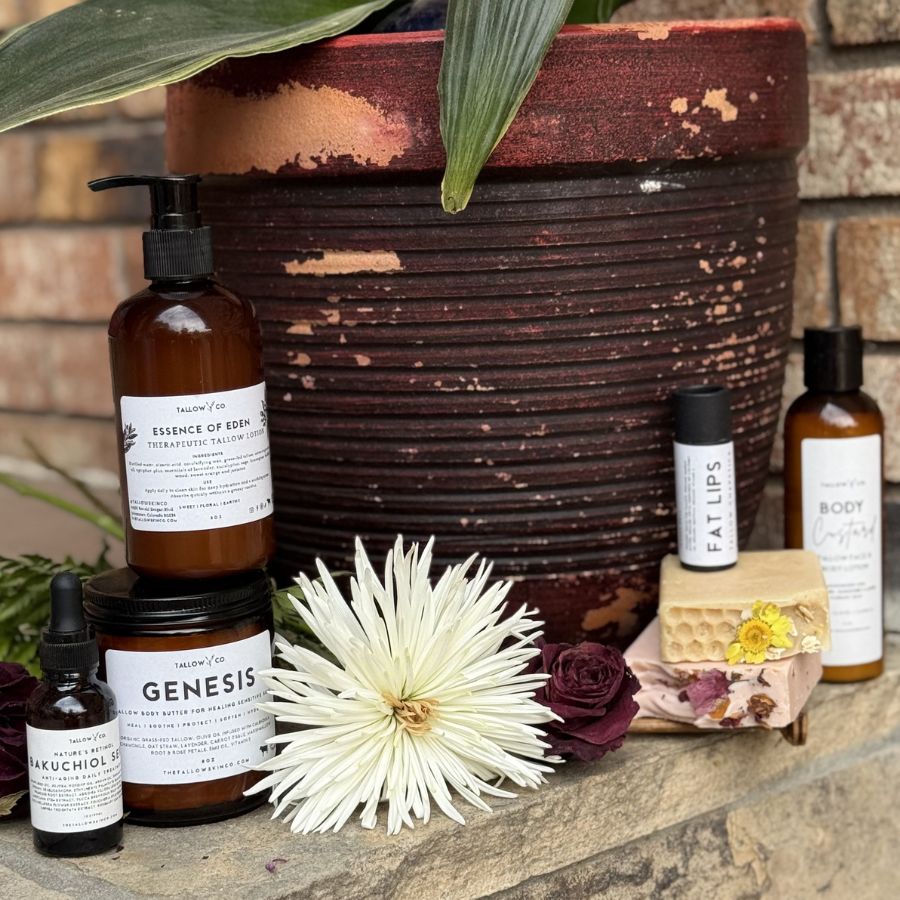 A collection of Tallow Skin Co. products against a amber planter on stone steps outdoors. 