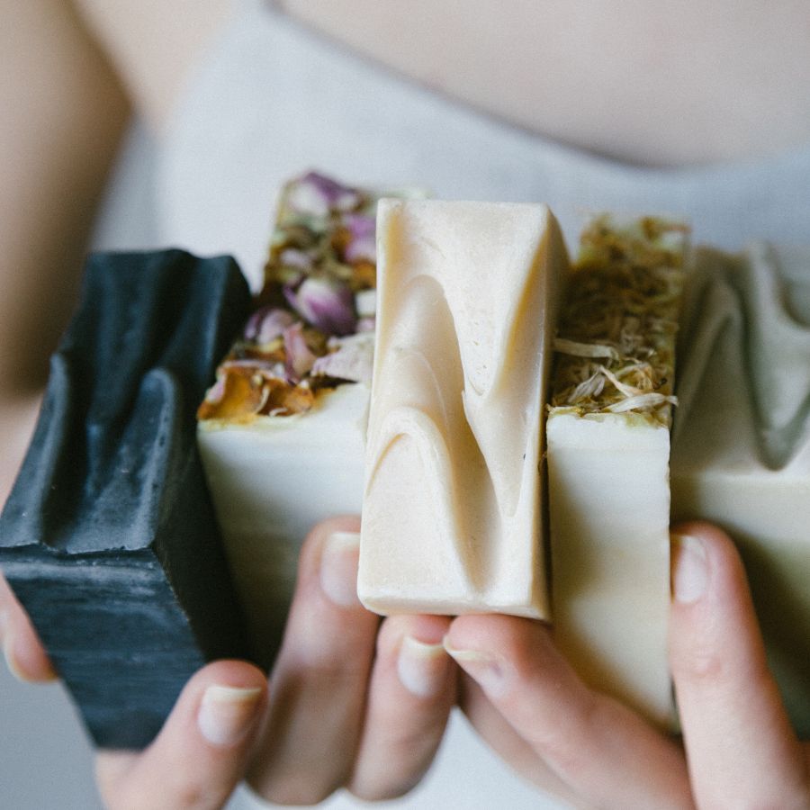 Hands holding various cold process artisan soaps.