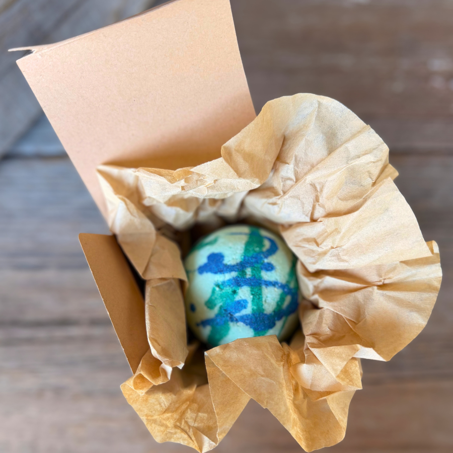 Dinosaur Surprise Bath Bomb packaged in a kraft gift box with natural tissue paper.
