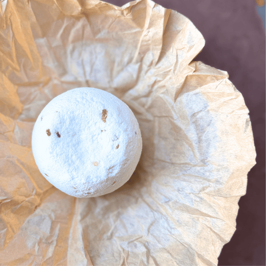 Jumbo Cold & Flu Relief bath bomb nestled in natural kraft tissue paper, showing its white surface and mineral flecks.