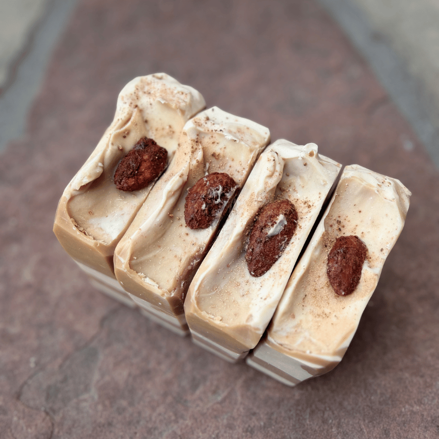 Image 1 — Overhead, almond toppings
Four handcrafted Almond Cookie tallow soap bars with creamy piped tops, candied cinnamon almonds, and cocoa-dusted detailing.