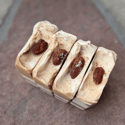 Image 1 — Overhead, almond toppings
Four handcrafted Almond Cookie tallow soap bars with creamy piped tops, candied cinnamon almonds, and cocoa-dusted detailing.