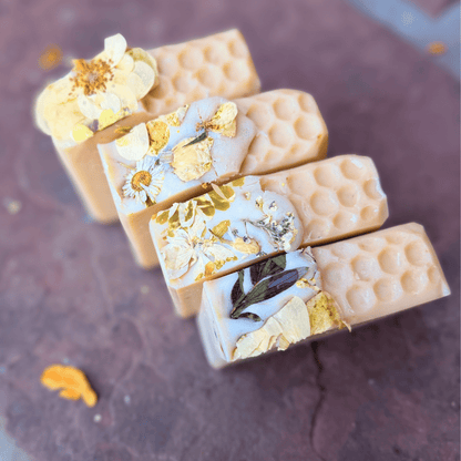 Four handmade Apricot Freesia tallow soap bars with honeycomb texture and dried botanical flowers