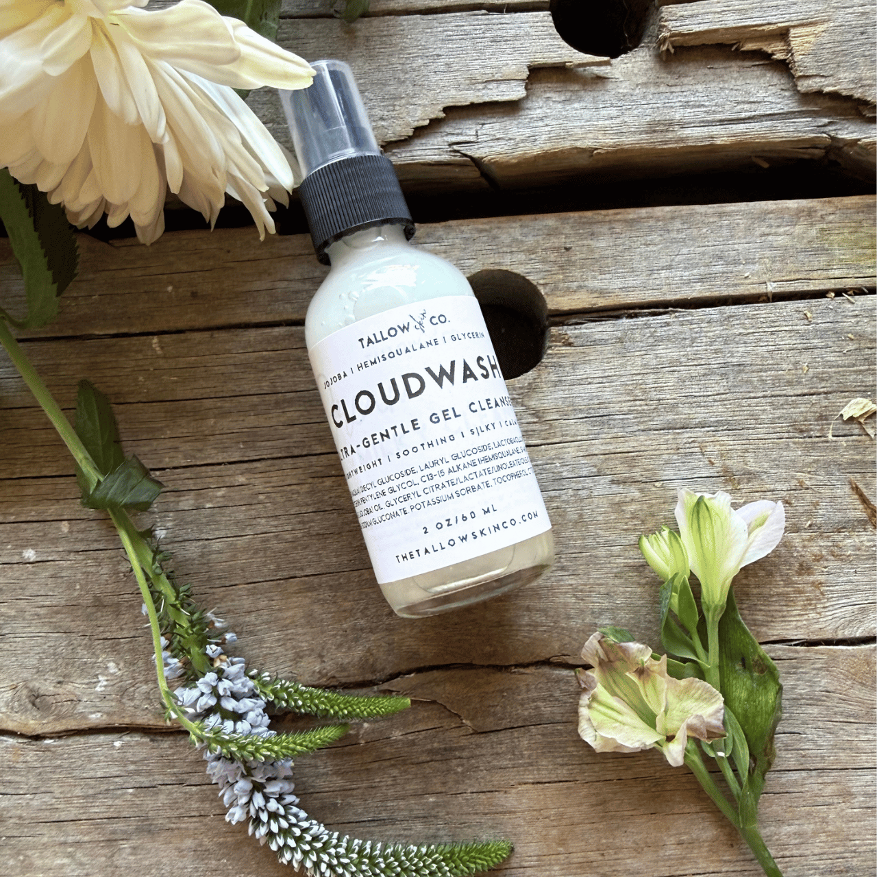 Bottle of 'Cloudwash' on a wooden surface with flowers
