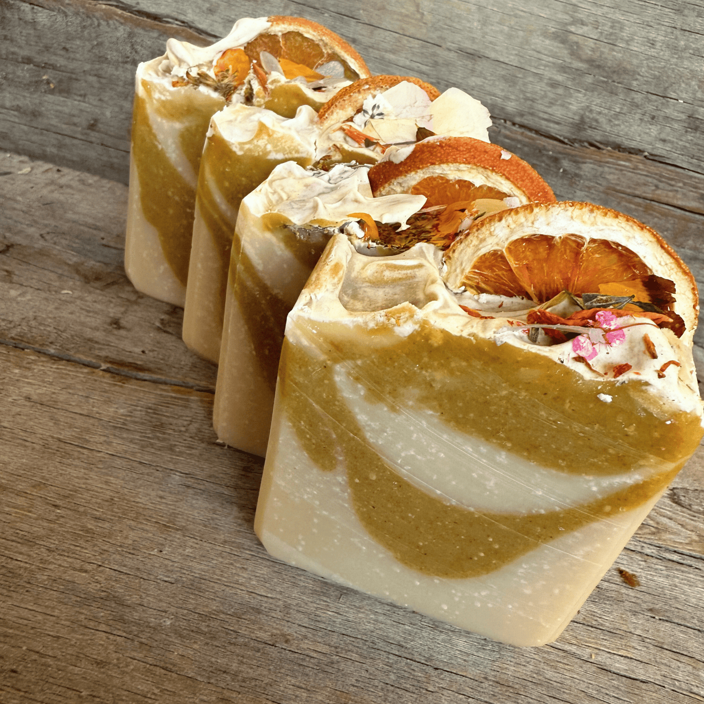 Multiple bars of Orange Terra, showcasing the tallow based skincare benefits, arranged on rustic barnwood to emphasize their natural ingredients.