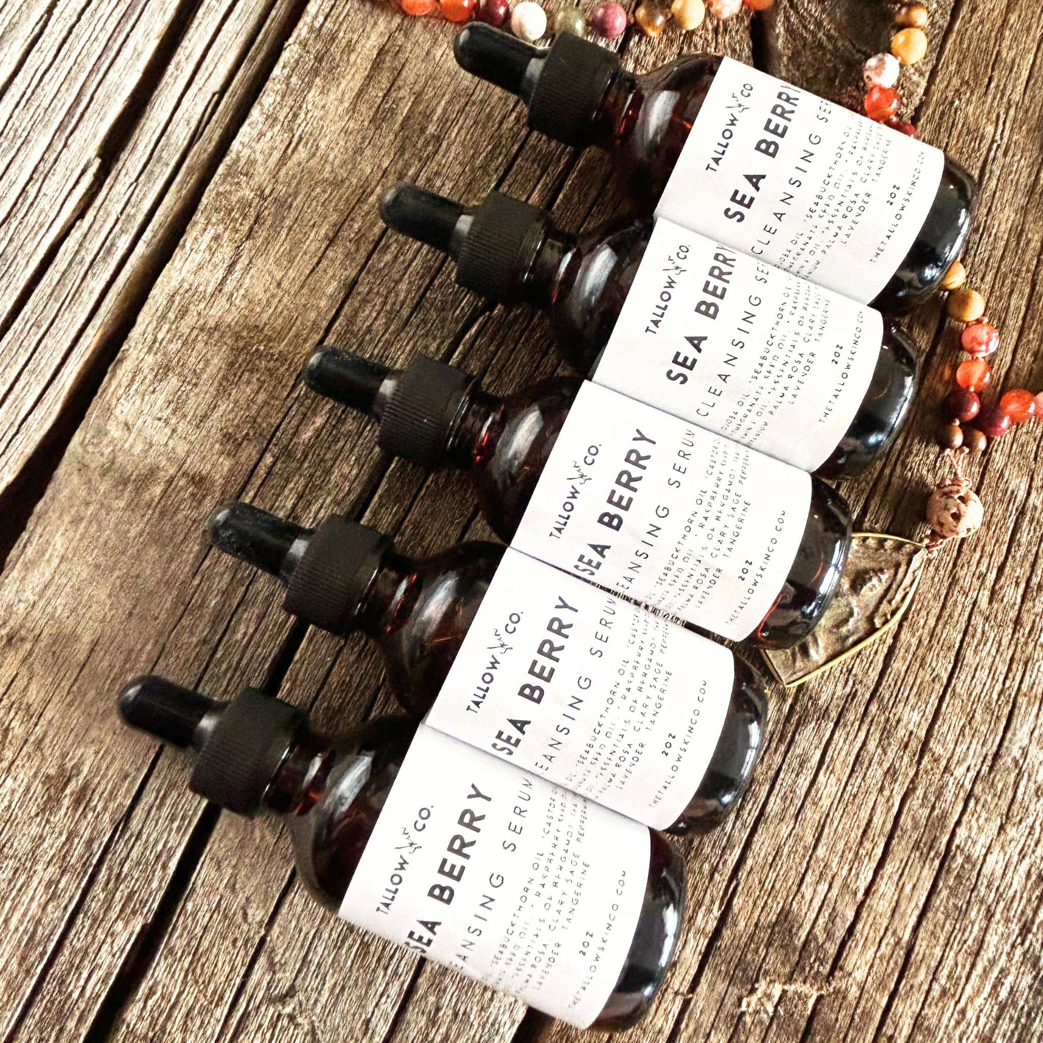Bottles of sea buckthorn oil cleanser laying on barnwood with a mandala.