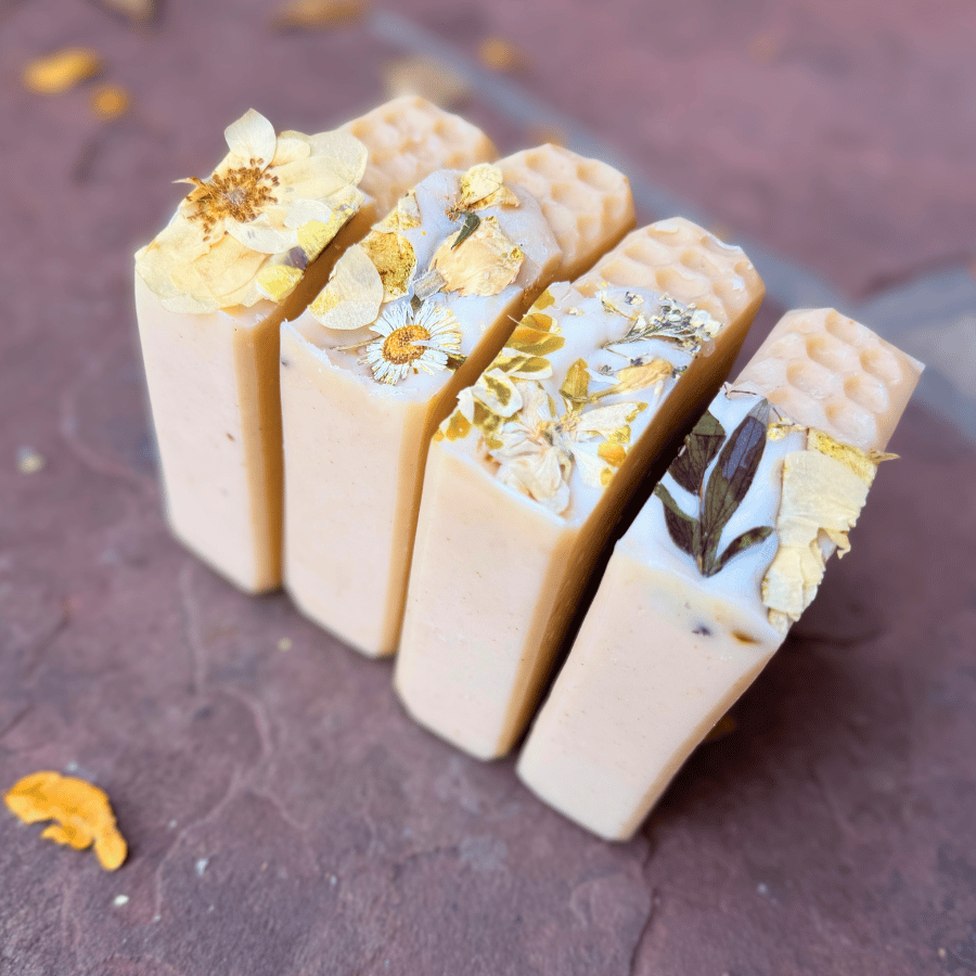Four Apricot Freesia tallow soap bars standing upright with delicate dried flowers and honeycomb details