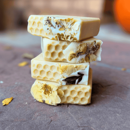 Four stacked honey-colored tallow soaps decorated with dried florals and textured honeycomb patterns