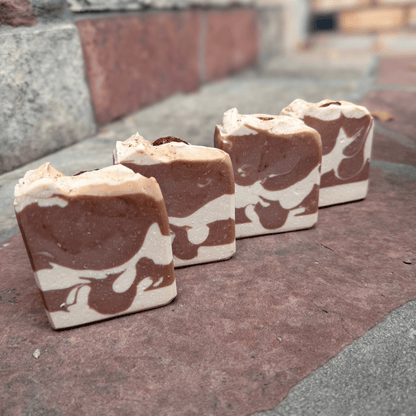 Four handmade Almond Cookie soap bars arranged diagonally, featuring rich cocoa brown and creamy white swirls with textured tops.