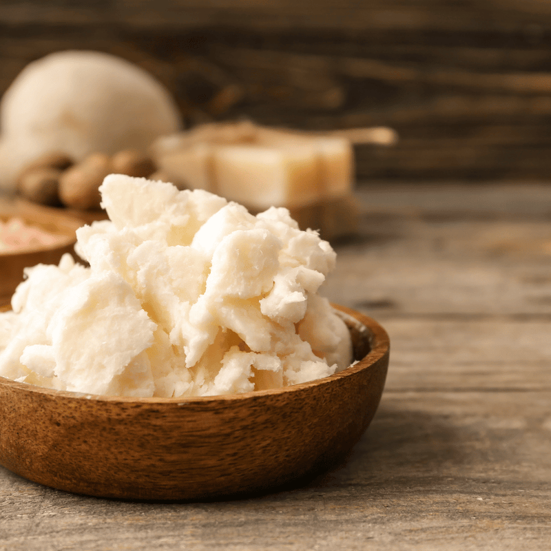 A wooden bowl of shea butter on a wooden surface