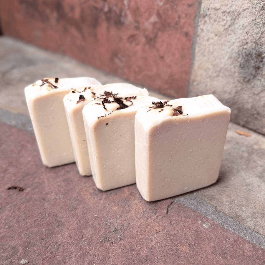 Four upright Tobacco & Bay Leaf pumice soap bars showing smooth, creamy ivory faces and rustic tobacco-topped edges, made with grass-fed beef tallow.