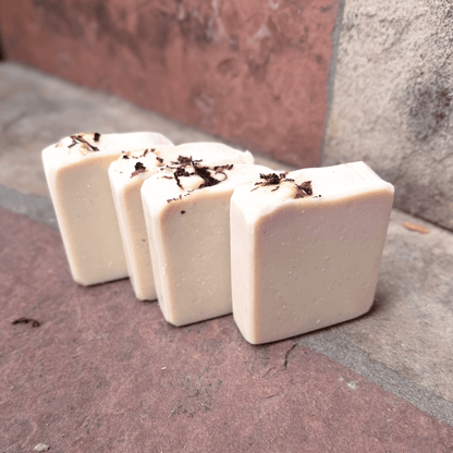 Four upright Tobacco & Bay Leaf pumice soap bars showing smooth, creamy ivory faces and rustic tobacco-topped edges, made with grass-fed beef tallow.